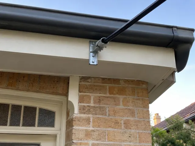 Overhead service cable and bracket on a house fascia under the eaves in West Ryde